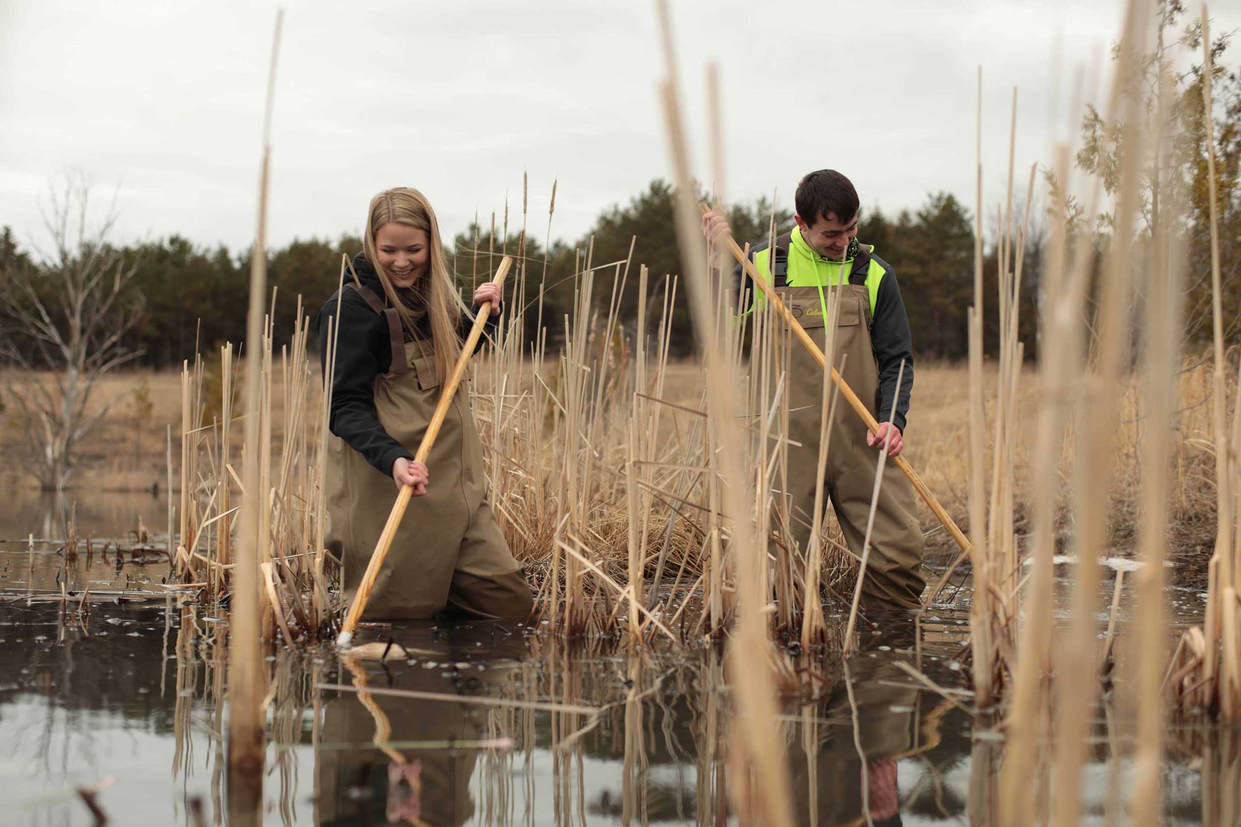 Students in waders working in pond